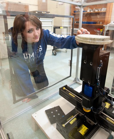 A UMass Lowell female Civil Engineering student putting something into a cylander