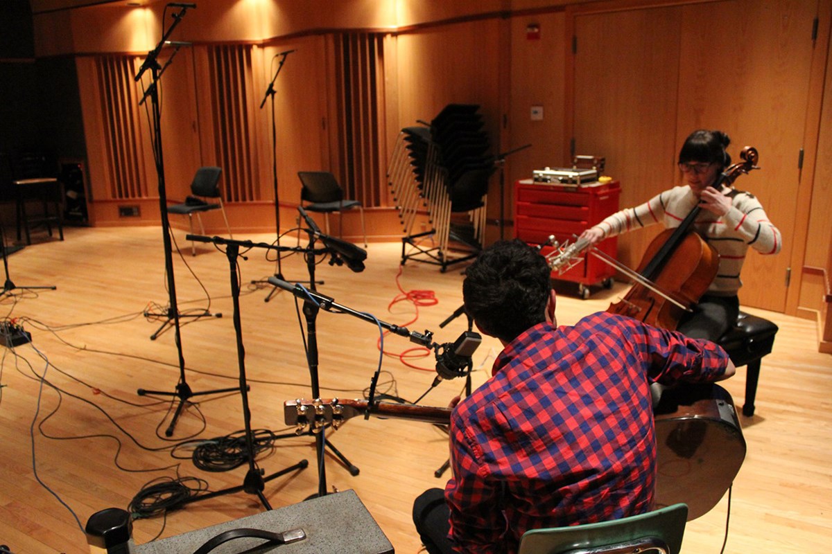 A female and male student playing instruments in the studio and recording music.