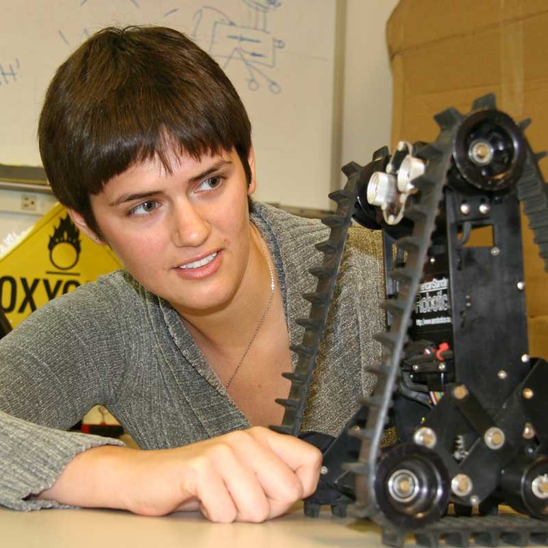 Student looking at a treaded robot in a computer science classroom at UMass Lowell