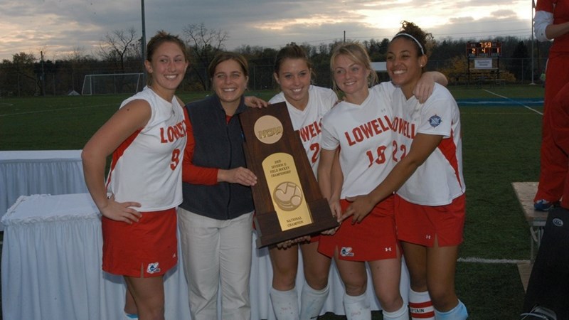 The 2005 NCAA Division II Championship winning field hockey team shows off their trophy with their coach on the field in uniform