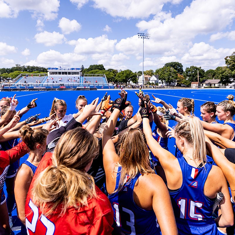 Field hockey players raise hands together