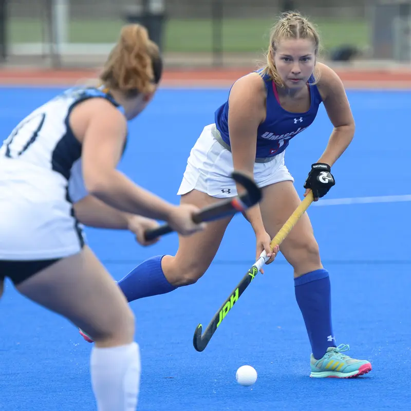A UMass Lowell field hockey player moves the ball past the opposing team's defense player.