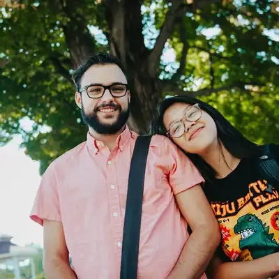 Young woman puts her head on shoulder of young man under tree