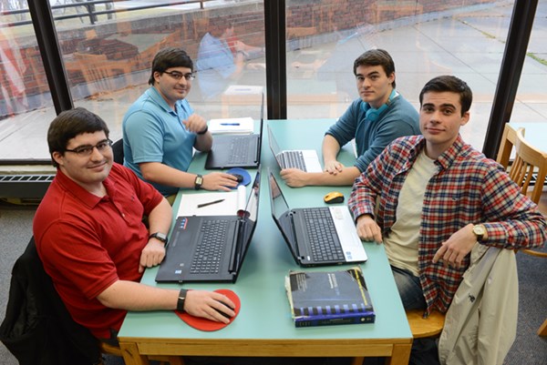 The four Forsyth brothers sit at a table in O'Leary Library on their laptops