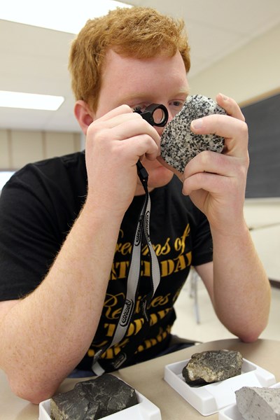 geology-male-student-magnifying-glass-rock