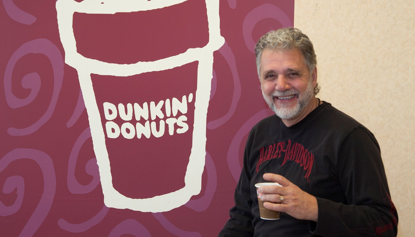 George Zografos holds a cup of coffee in one of his former Dunkin' Donuts locations on Cape Cod