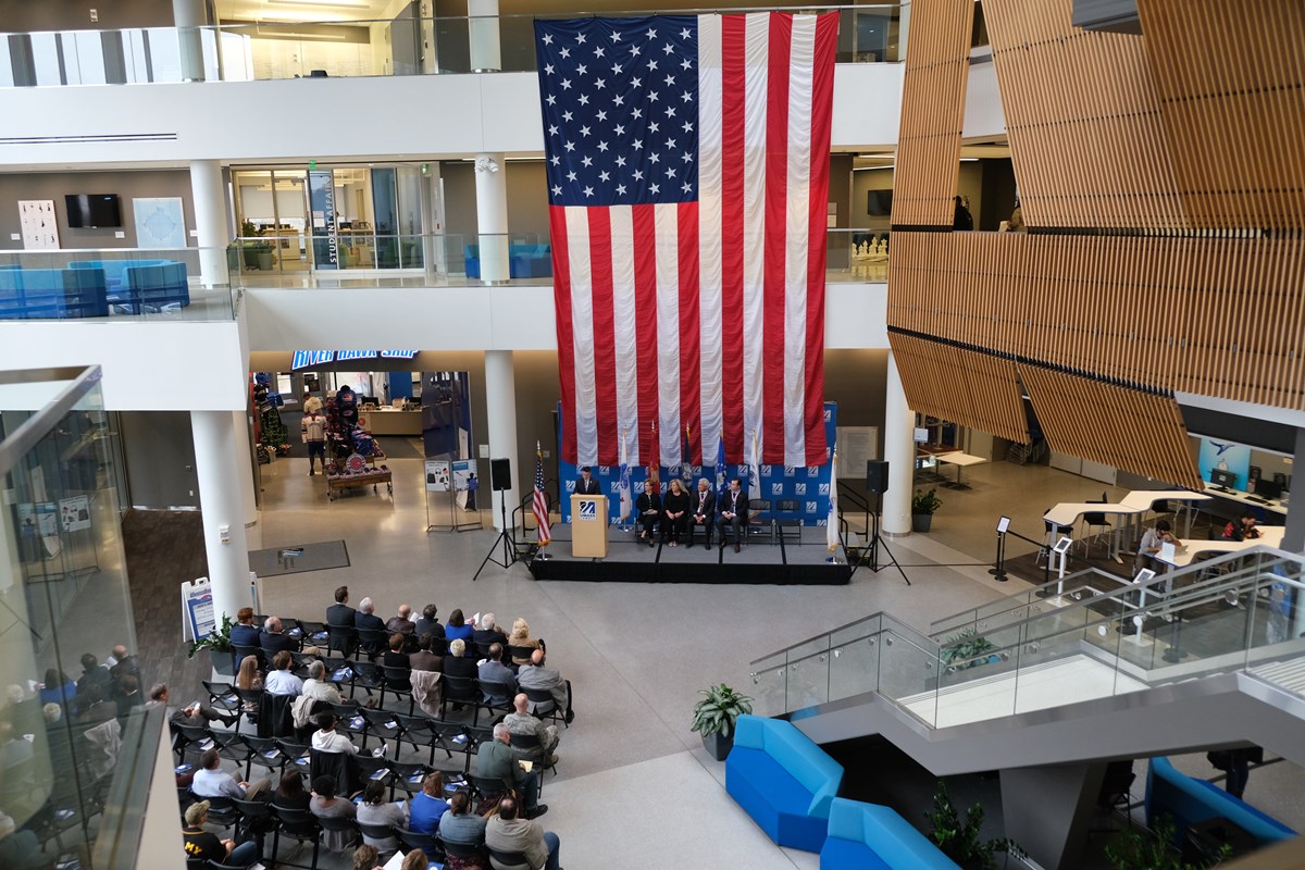 As seen from above: a giant US Flag hangs down in the atrium of University Crossing during the Veteran's Day Flag Ceremony in 2018.