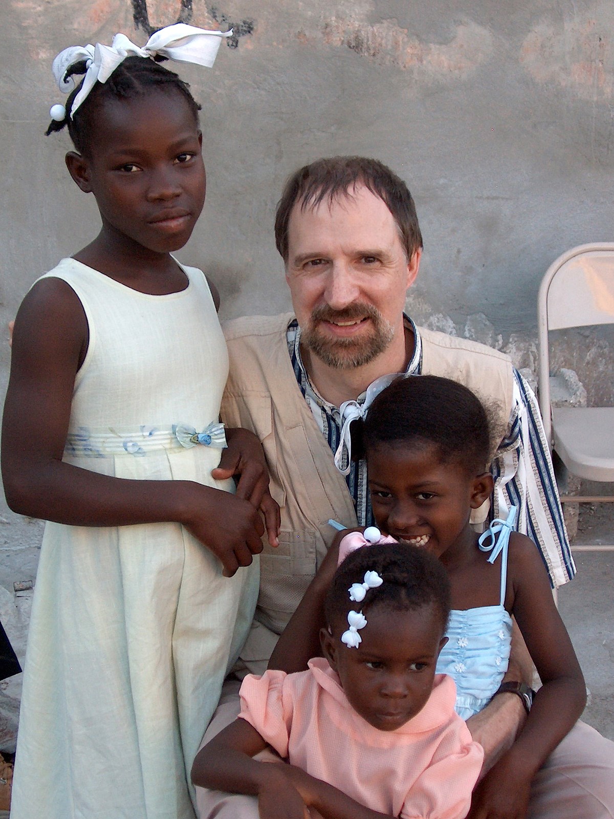 UMass Lowell Professor and Director of the Haiti Development Studies Center poses with three young Haitian girls.
