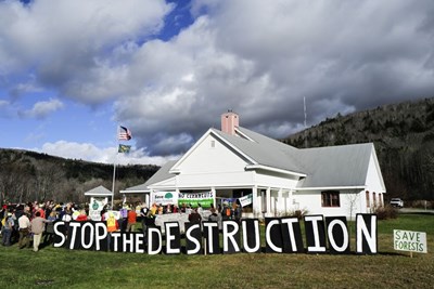 People protesting with big sign that says Stop the Destruction