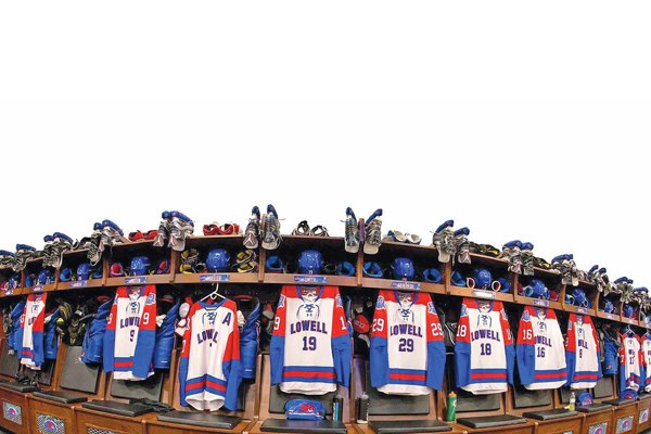 UMass Lowell hockey jerseys and skates hang in the River Hawks locker room