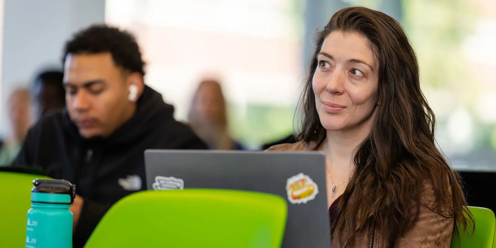 A graduate student looking up, over her computer, in a class at UMass Lowell.