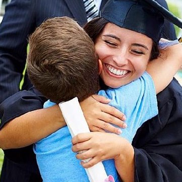 Woman in graduation garb hugging young boy