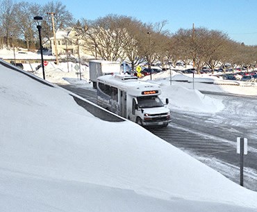 A green North Shuttle running during the winter in Umass Lowell. 