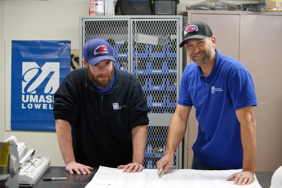 Two bearded men wearing baseball caps reviewing large plan