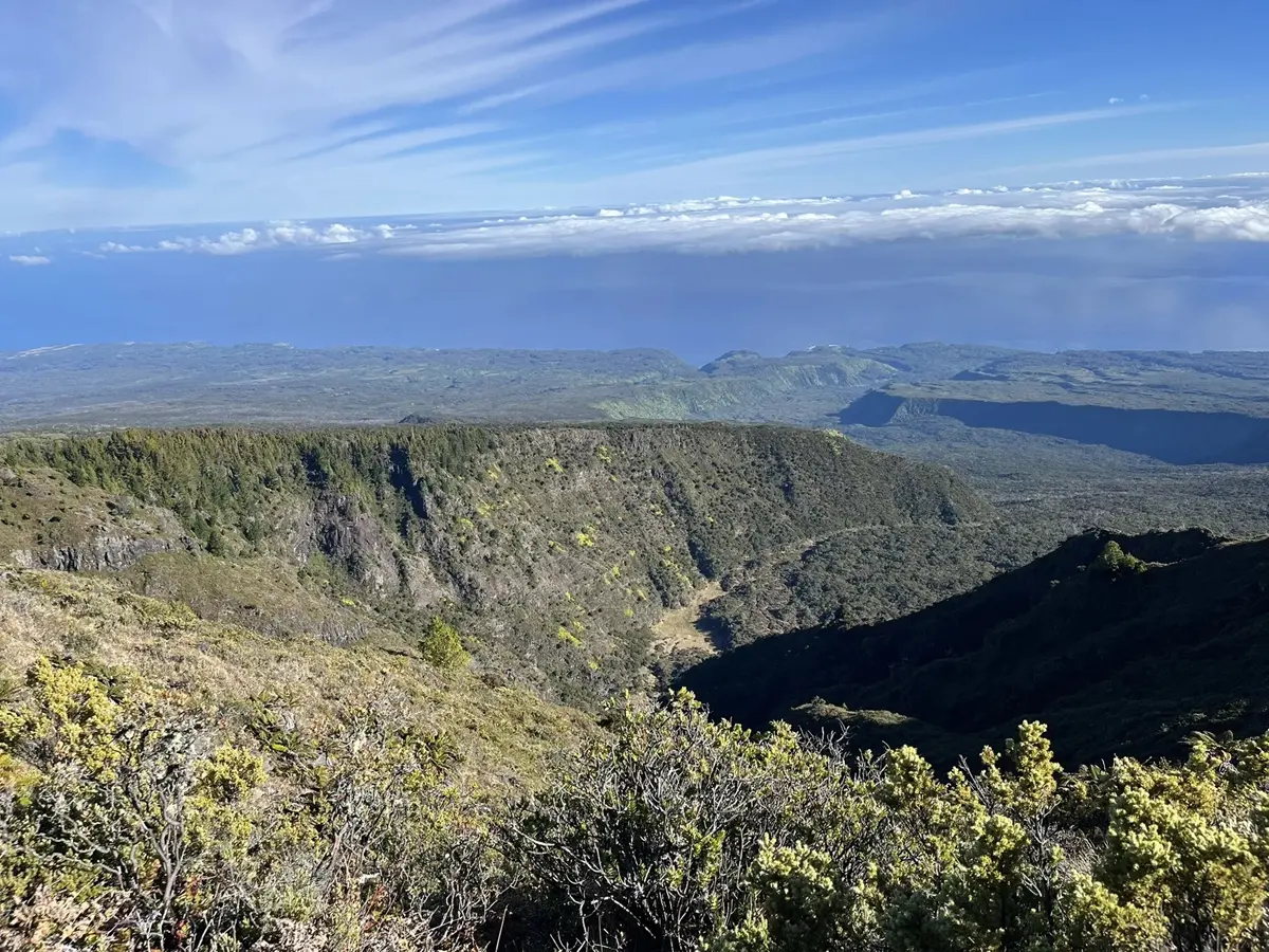 A huge vista of a ridge dropping down to a valley, and the far edge drops off to the ocean and sky.