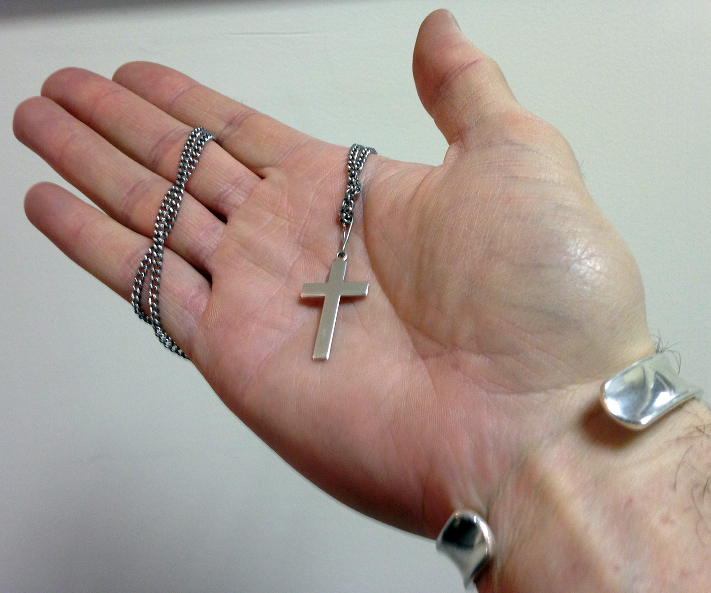 Hand holding a crucifix/cross necklace.