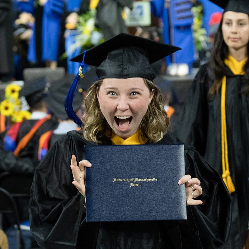 Excited young woman holding up her diploma