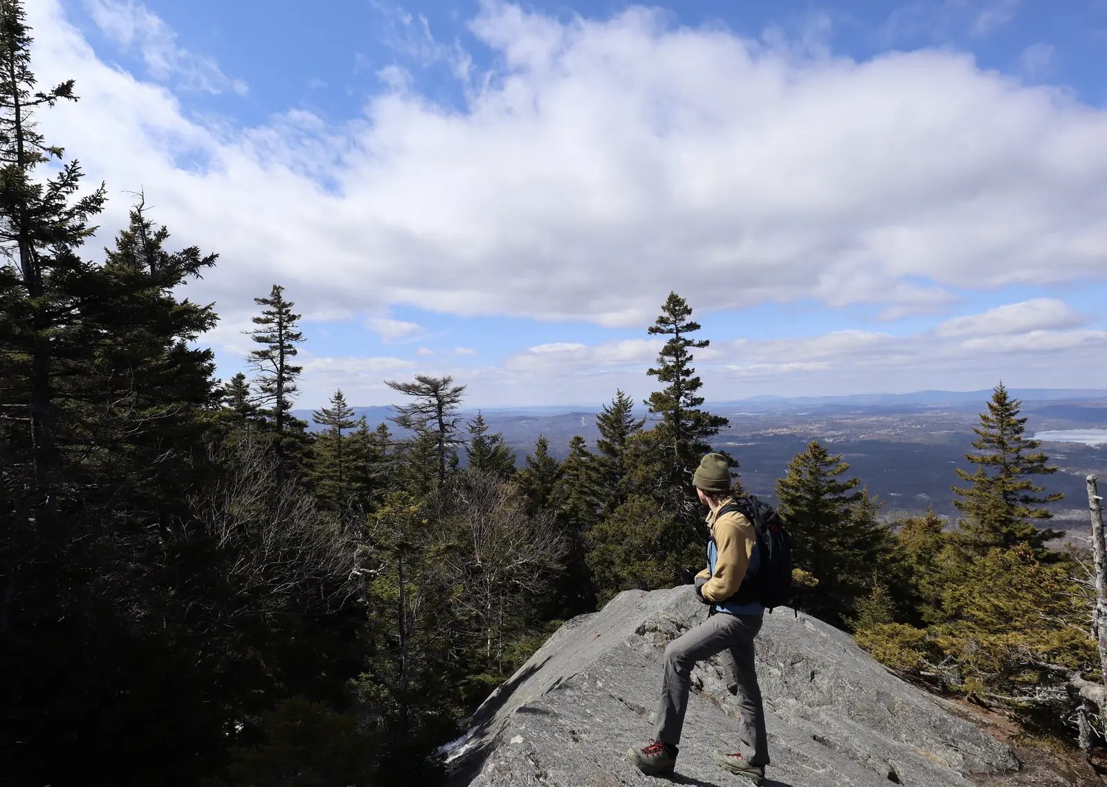 One person stands on a rock admiring the distant view and the sky. 