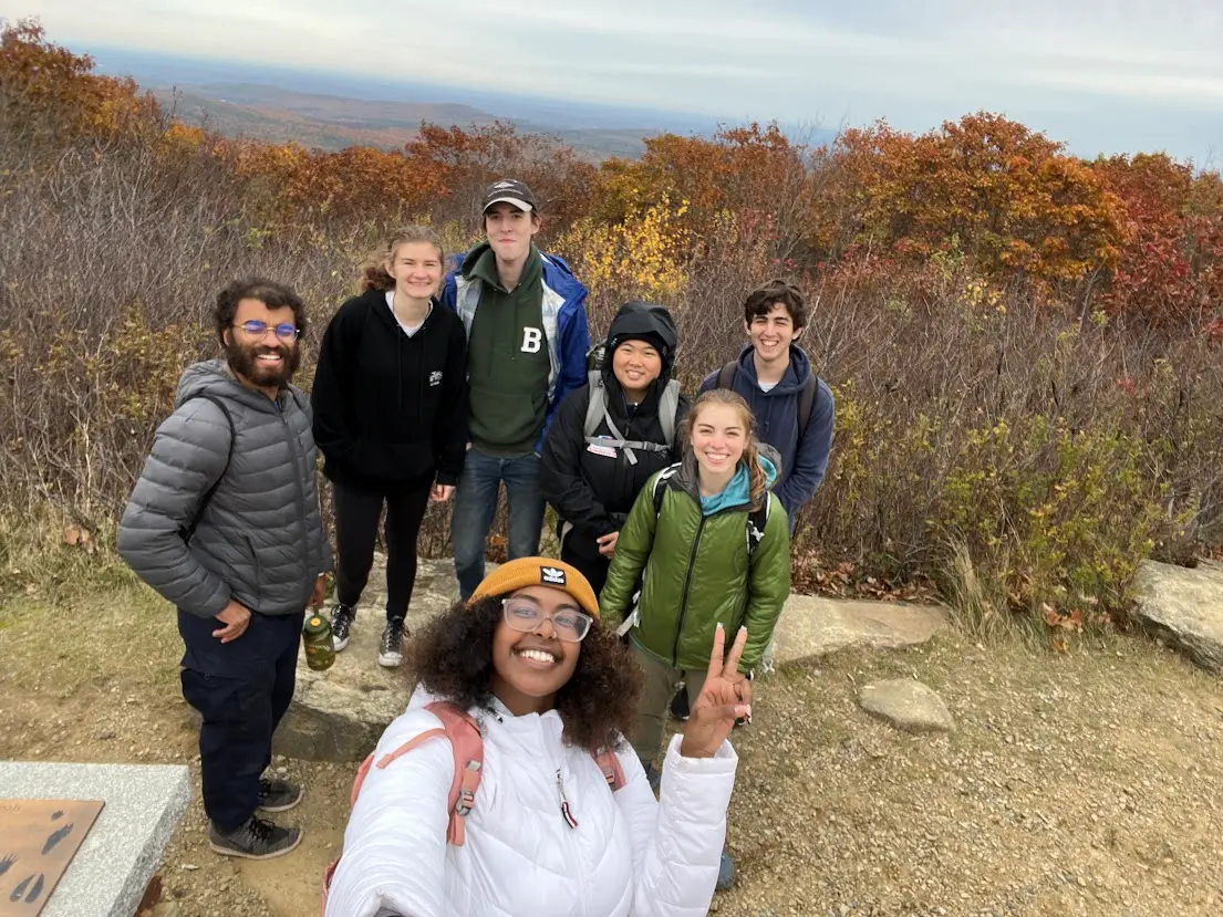 a small group smiles atop a viewpoint surrounded by fall colors