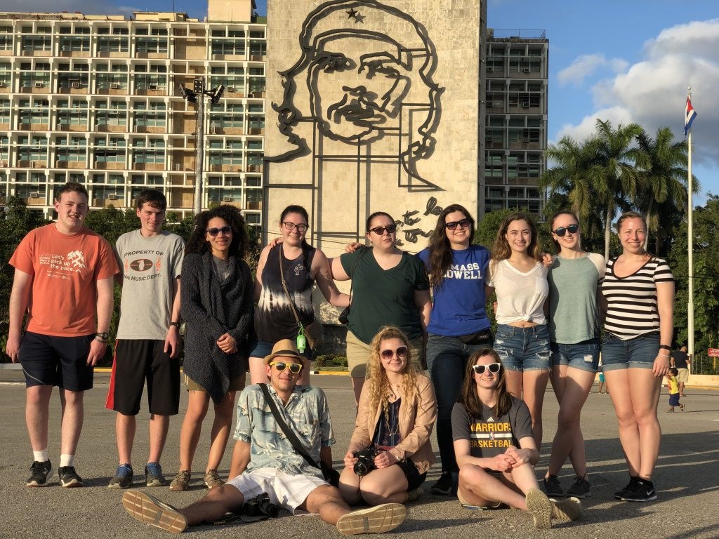 Honors students stand in Revolution Square in Havana, Cuba, in front of a large portrait of Che Guevara.