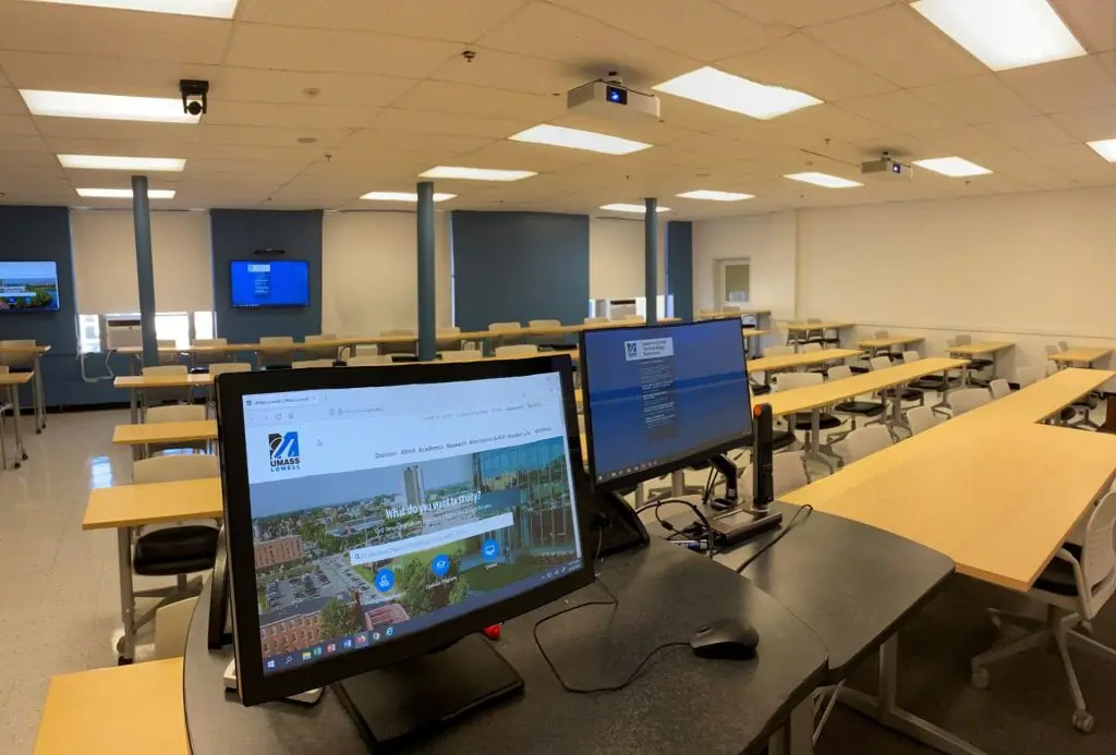 Classroom with smart podium, monitors, and projectors.