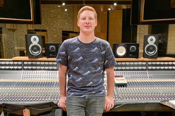 Luke Bilodeau standing in front of a sound board in a recording studio