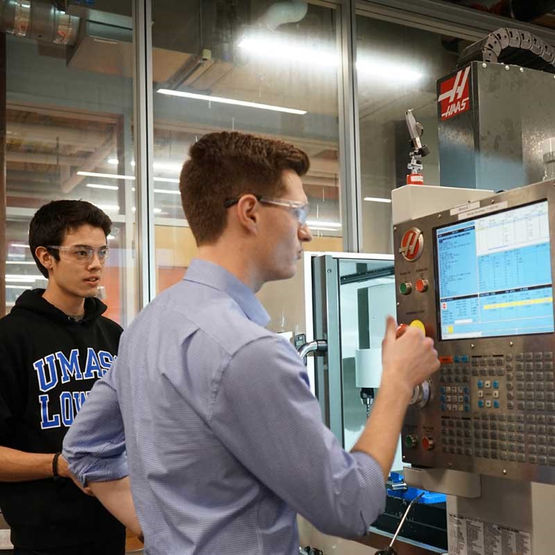 Two industrial engineering students work with equipment in a UMass Lowell lab