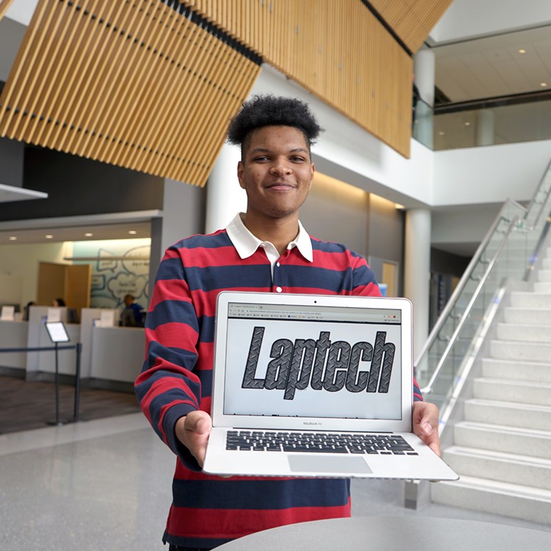 Joel Dabady holds a laptop with the Laptech logo on the screen