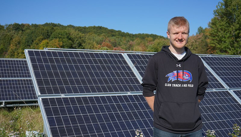 Joshua Walsh standing in front of solar panels