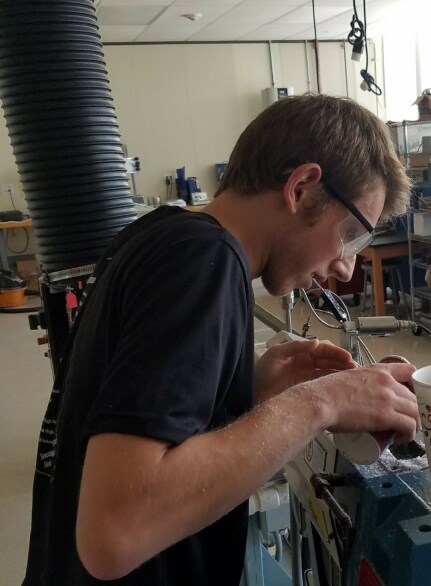 Plastics engineering major Justin Carbone works on an extruder during a development trial