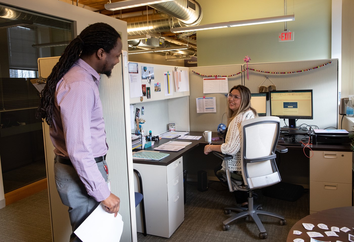 Two HR staff members talk in cubicle