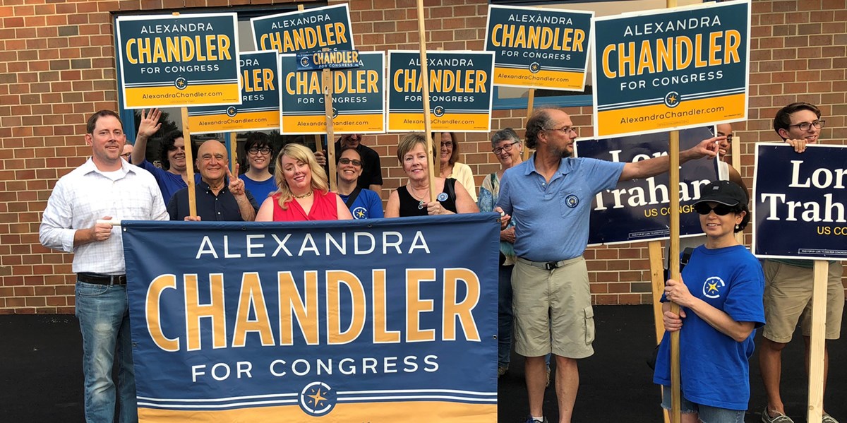 Lauren Young with a group of people at poll-signing holding a banner and signs for Alexandra Chandler, who is competing in the Democratic primary for Massachusetts’ 3rd Congressional District