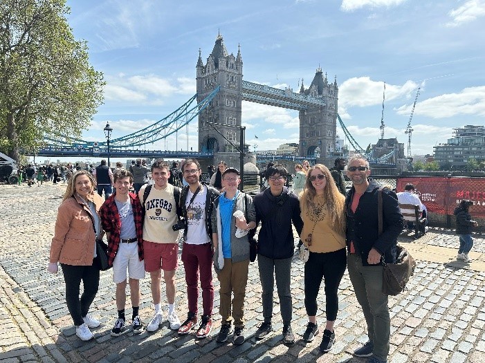 Students standing on cobblestone streets with London Tower Bridge in background.