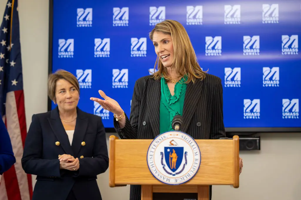 U.S. Rep. Lori Trahan speaks at a podium as Massachusetts Gov. Maura Healey looks on.
