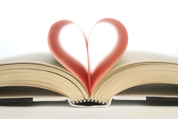 An open book with two pages folded inward to form a heart shape