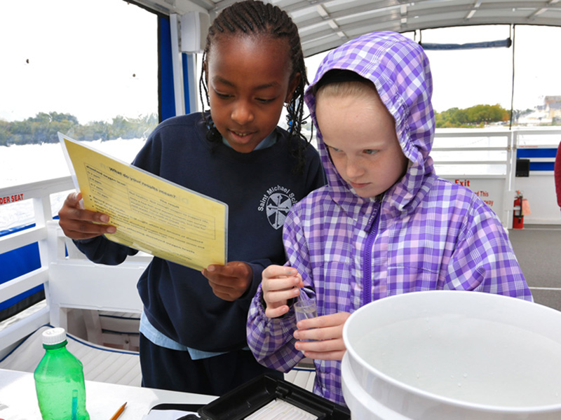 Lowell fourth graders examine water samples on boat