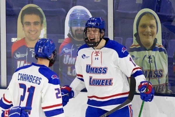 UML hockey players celebrate in front of cardboard cutouts of fans