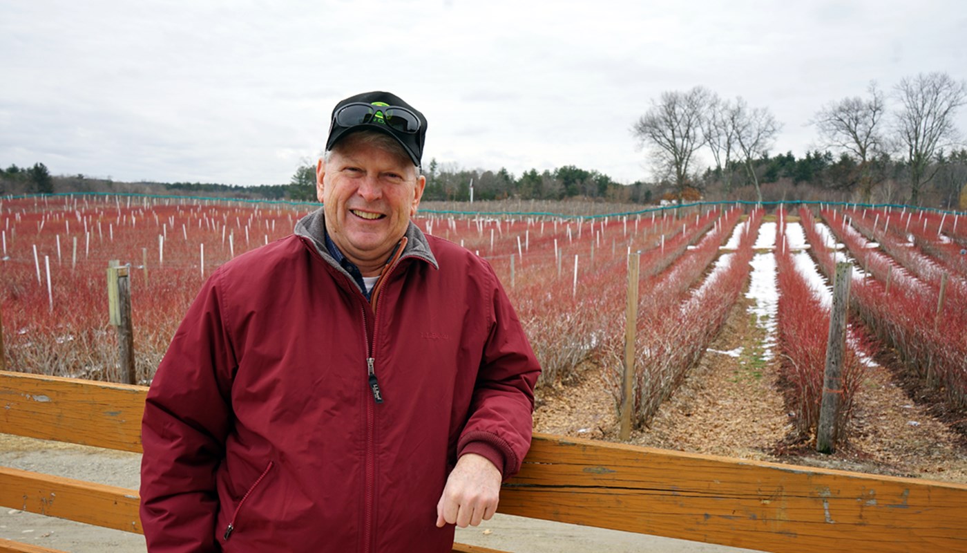 Mark Parlee standing in front of rows of crops at his farm in Tyngsboro