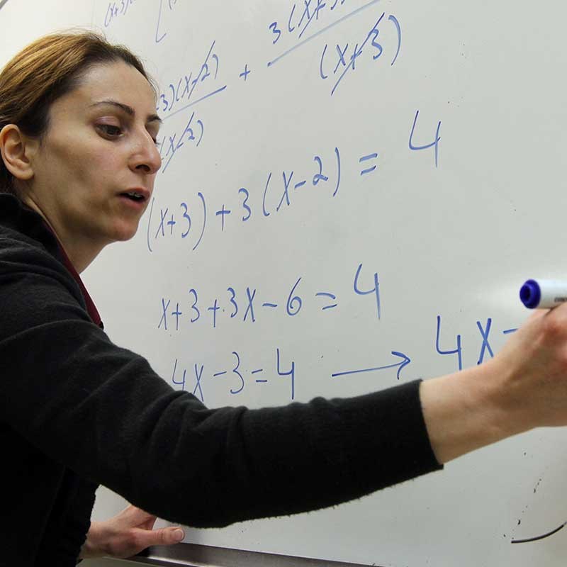 UMass Lowell math professor writes an equation on a whiteboard
