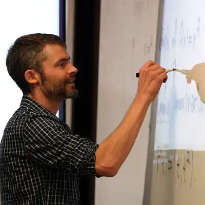 UMass Lowell math professor writes equations on a whiteboard.