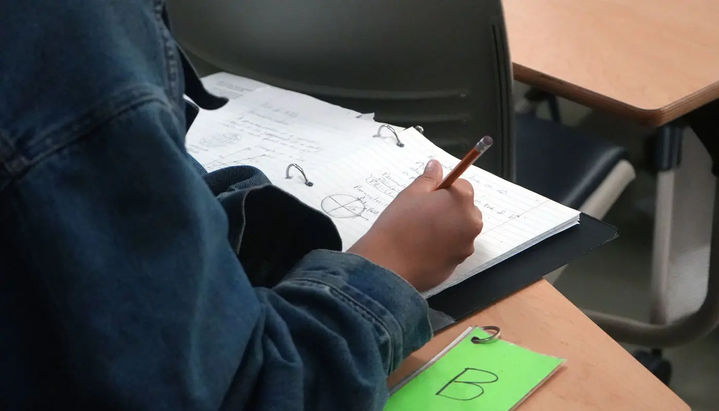 Close up of a student writing math equations in a notebook.