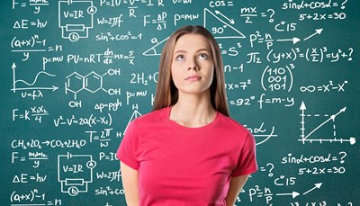 woman in front of blackboard with math, science formulas
