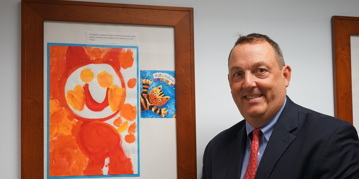 Woburn superintendent Matthew Crowley stands in front of artwork a kindergarten student did after reading the book "Cat's Colors"