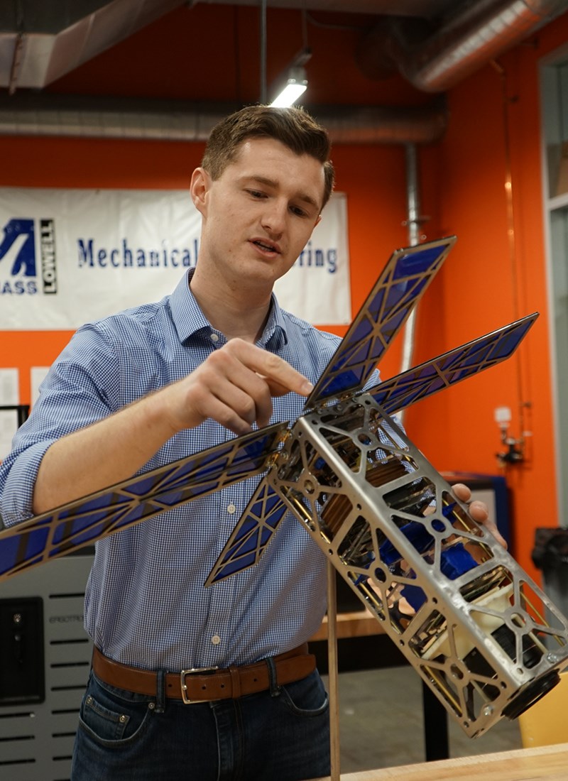 Matthew Clancy holds his CubeSat in a UMass Lowell's MakerSpace