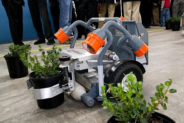 Wheeled robot picking up a plant.