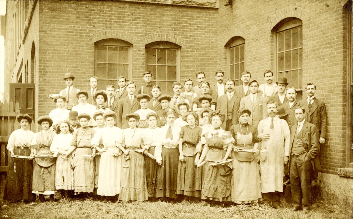 Group of mill workers in front of brick mill