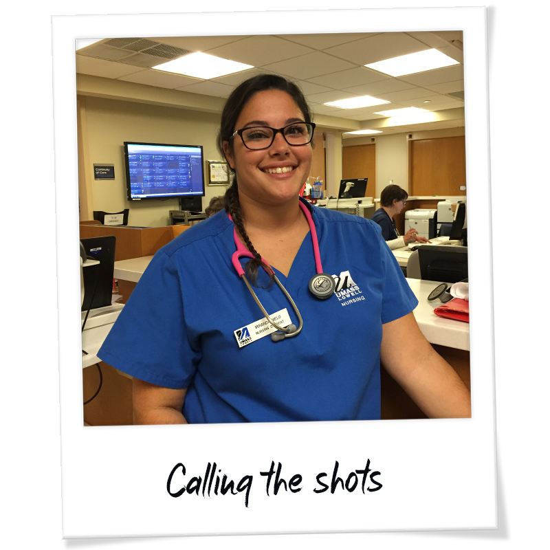 "Polaroid" photo of Miranda Melo in scrubs working at her clinical rotation at Lowell General Hospital in acute care- handwriting on frame reads "Calling the shots"