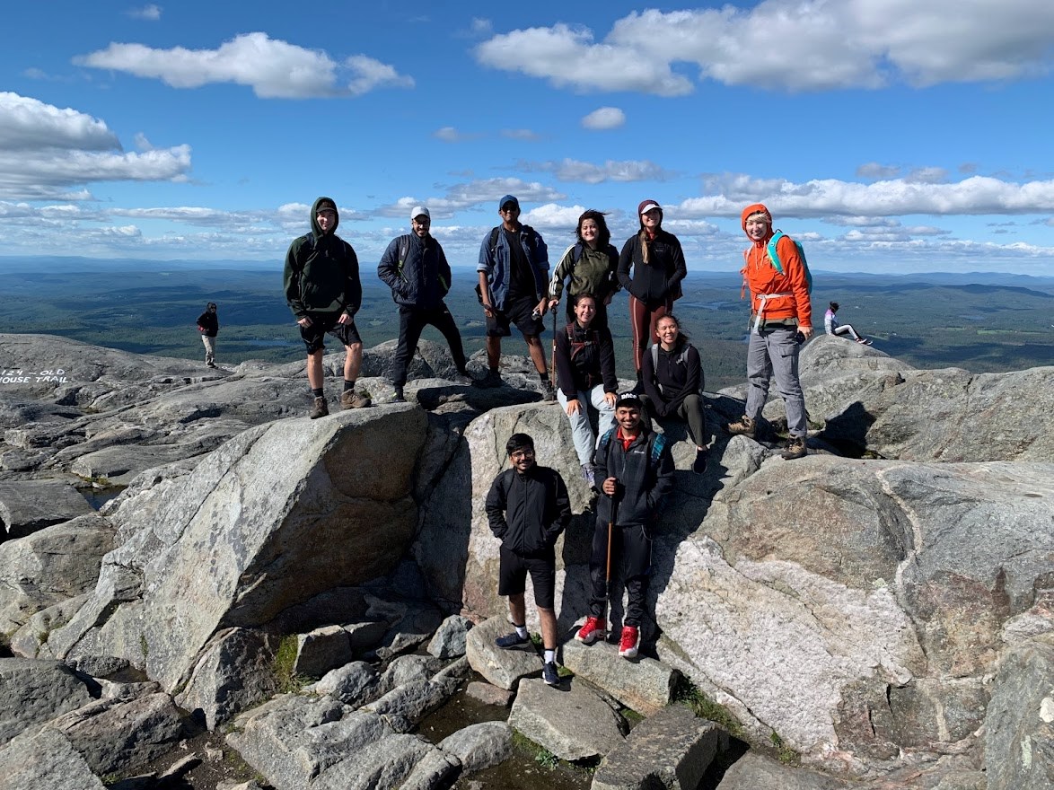 group of students smiling at the top of Monadnock Mountain with panoramic view beyond