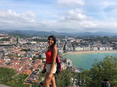 Study abroad student poses on Mount Urgull with beautiful beach, city and mountains in the background
