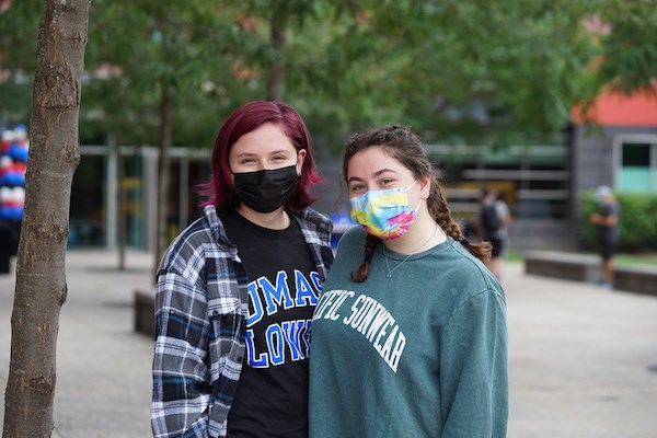 Two female students wearing facemasks pose for a photo